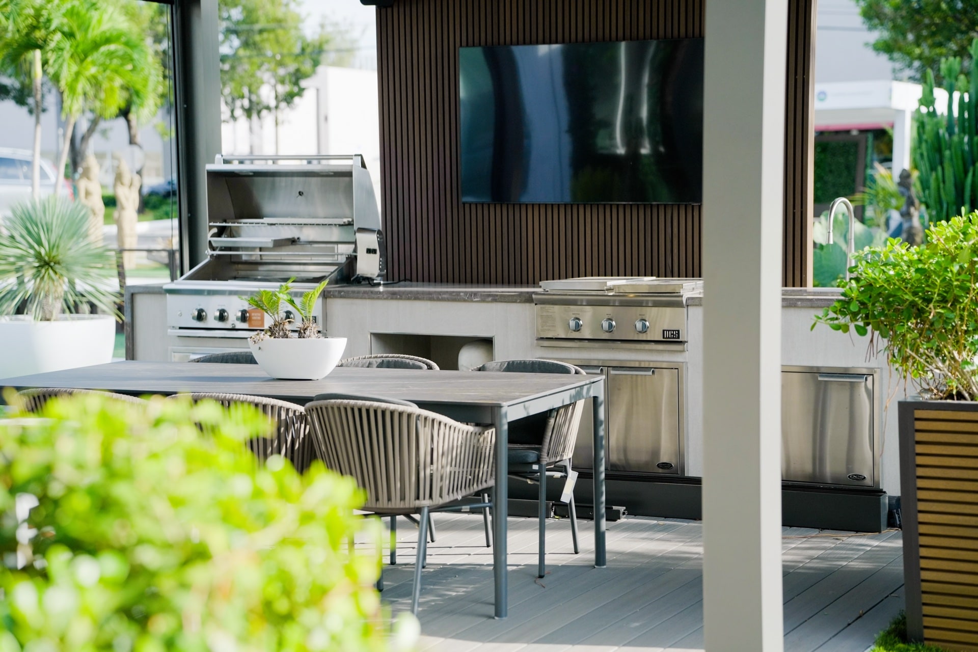 Built-in grill with the hood open next to a DCS side burner and refrigeration drawers in the Luxa Patio Doral showroom