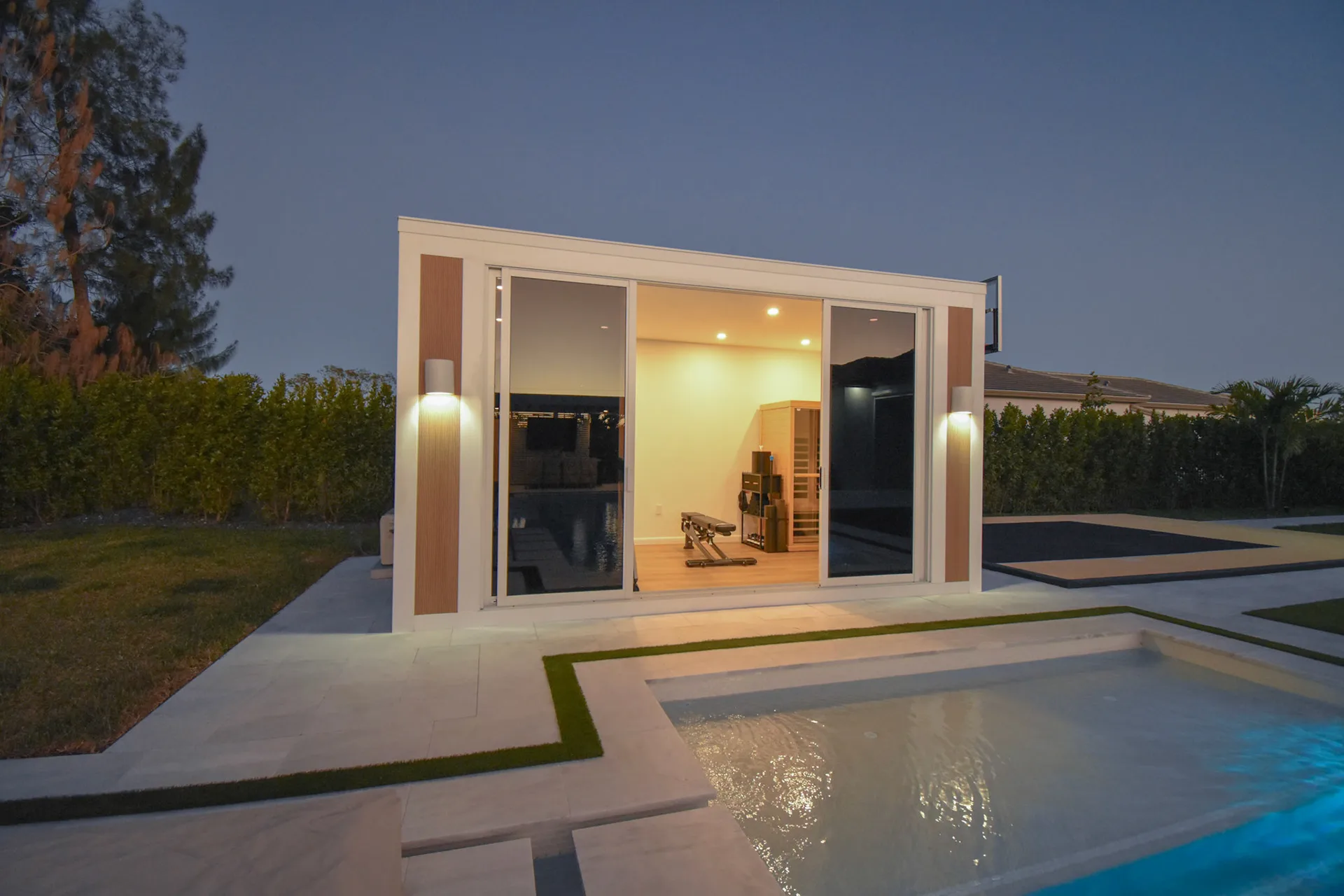 Luxapod at dusk — interior lit showing home gym and infrared sauna