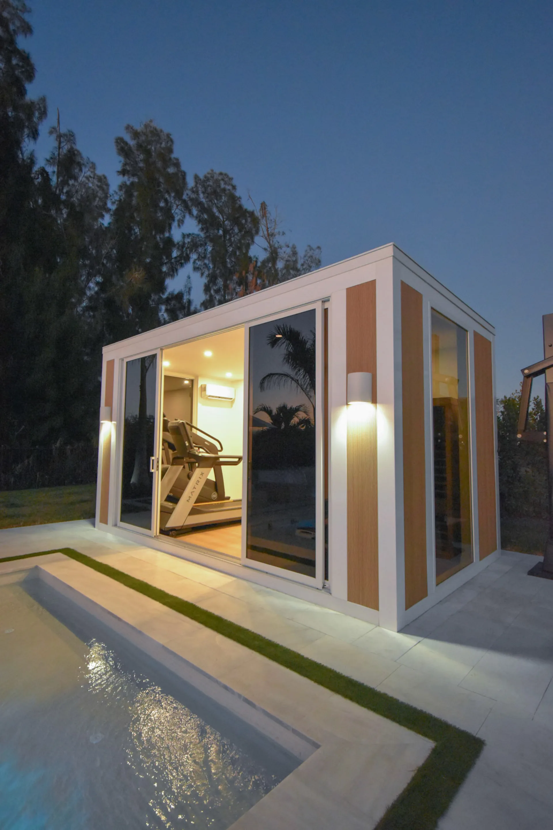 Luxapod at night — dramatic corner angle with wall sconces and aluminum framing