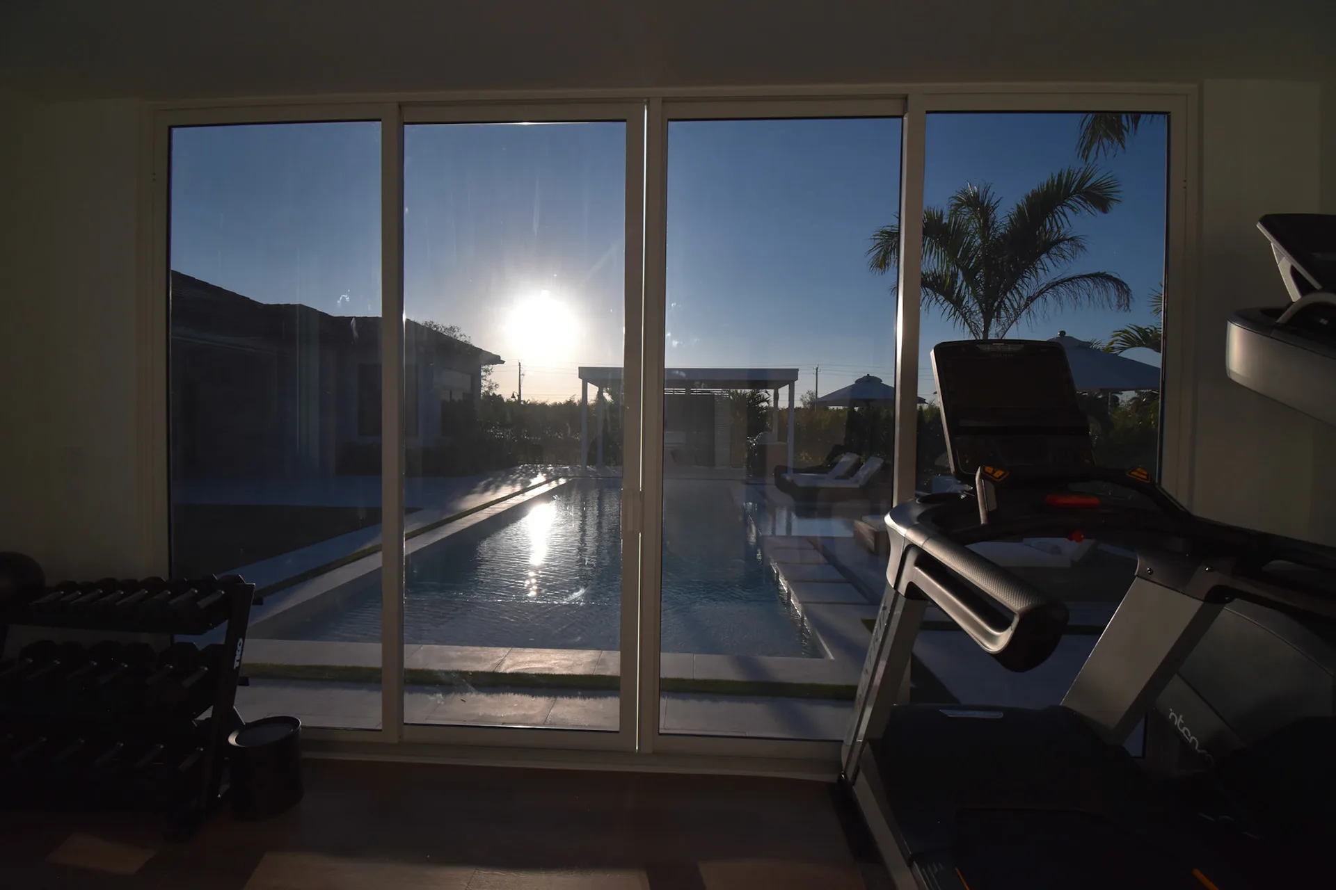 Luxapod interior — gym equipment with floor-to-ceiling glass wall overlooking pool