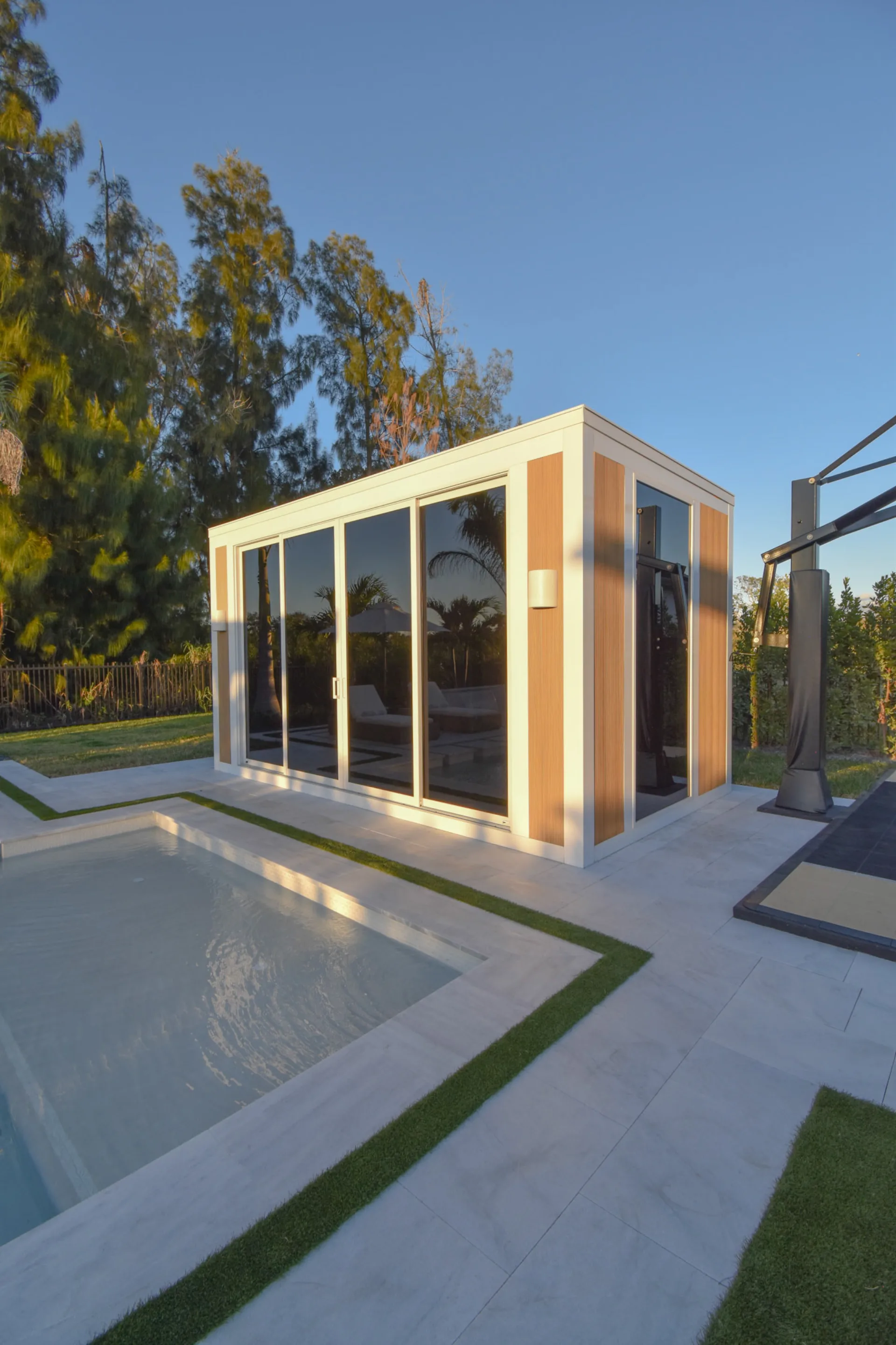 Luxapod at golden hour — structural detail of glass and wood panels poolside