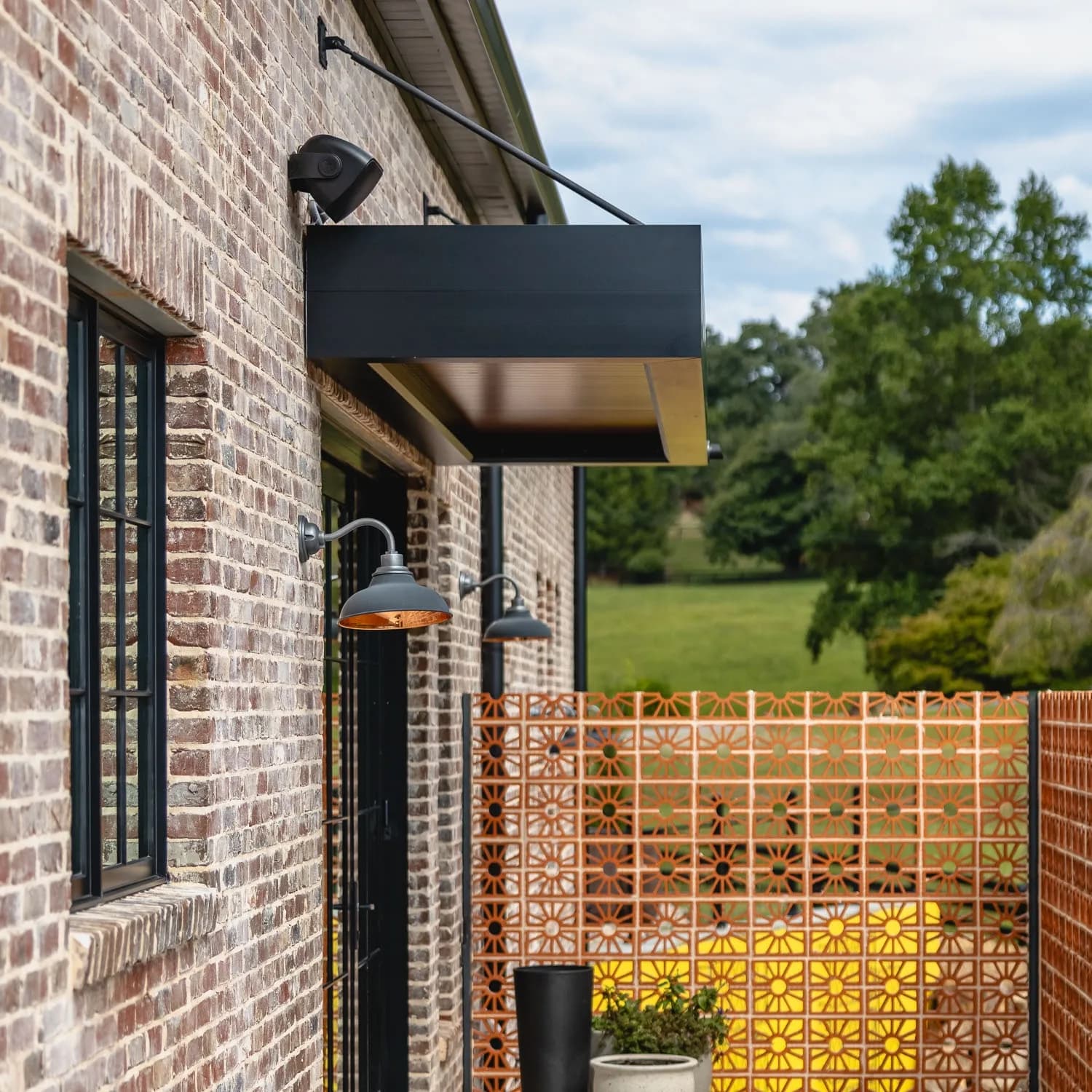 K-NOPY cantilevered overhang on a brick facade with industrial lamps