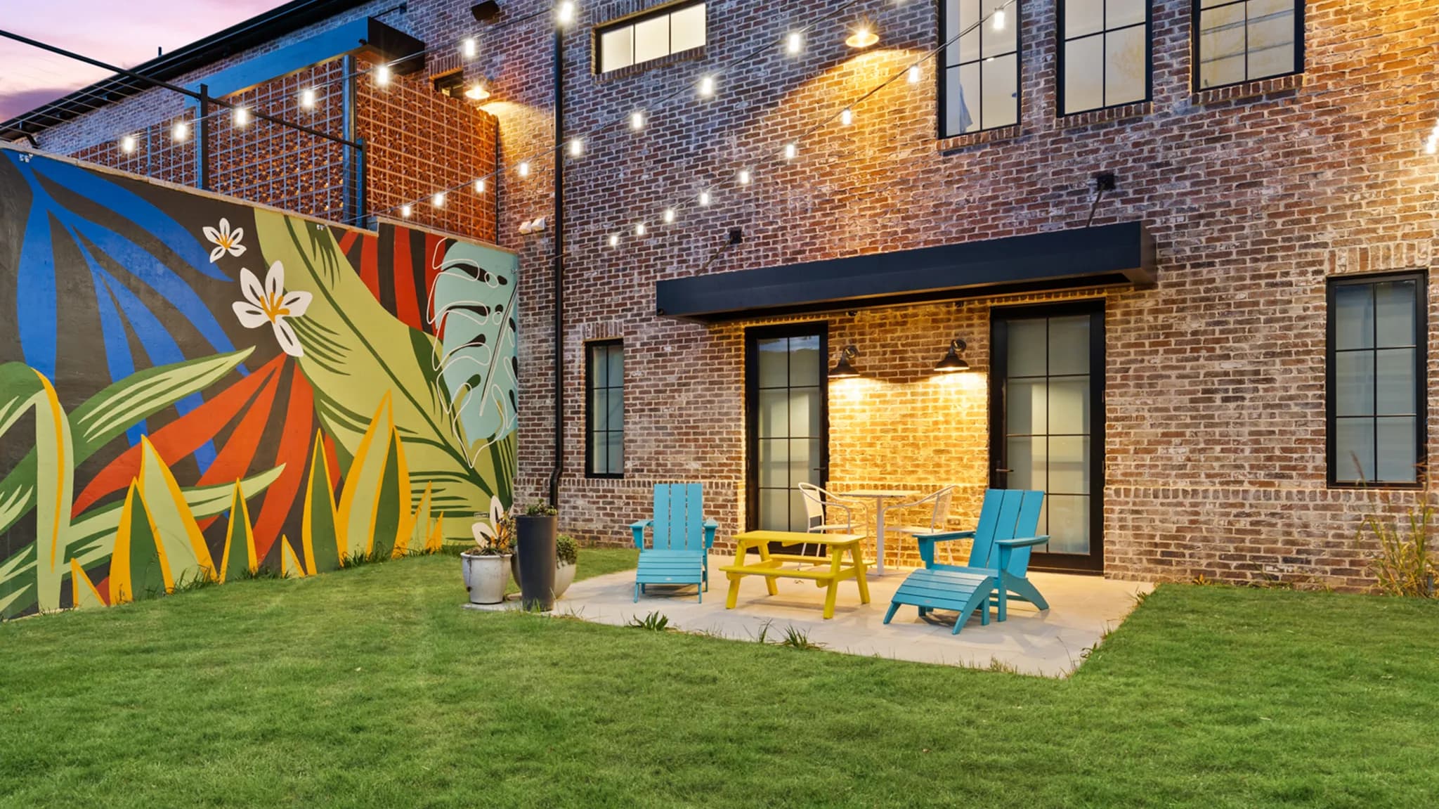 K-NOPY awning over a residential brick patio with mural and string lights