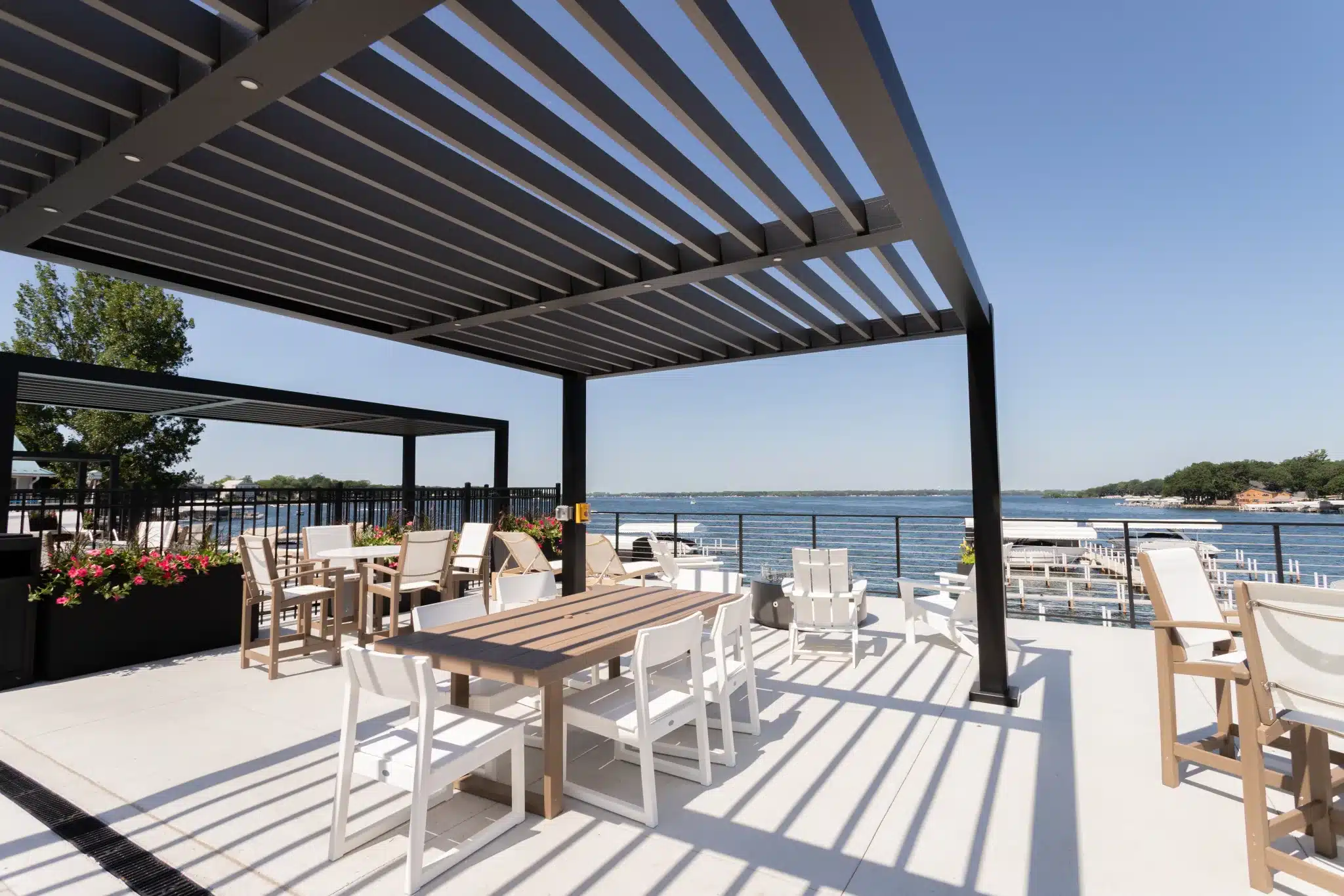 Black R-BREEZE pergola at a lakeside dining patio