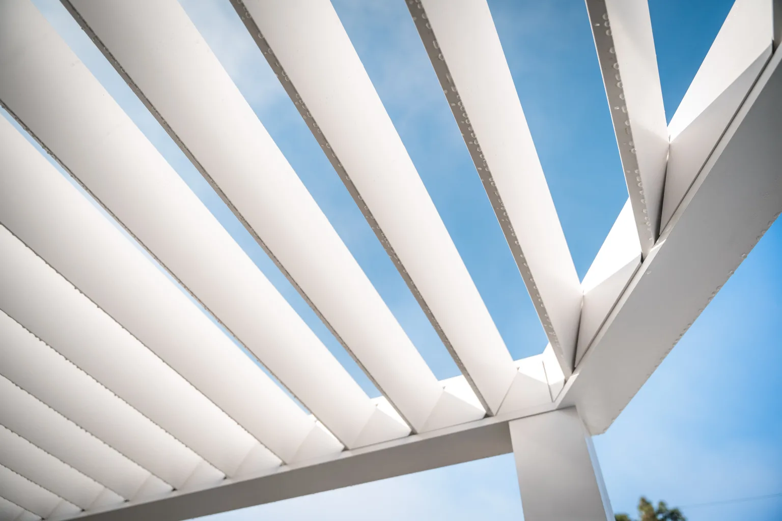 Close-up of R-BREEZE fixed aluminum louvers against a blue sky